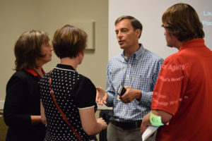 Tom Virden (center), the founder of Nymbl Science, speaks with attendees after the panel.